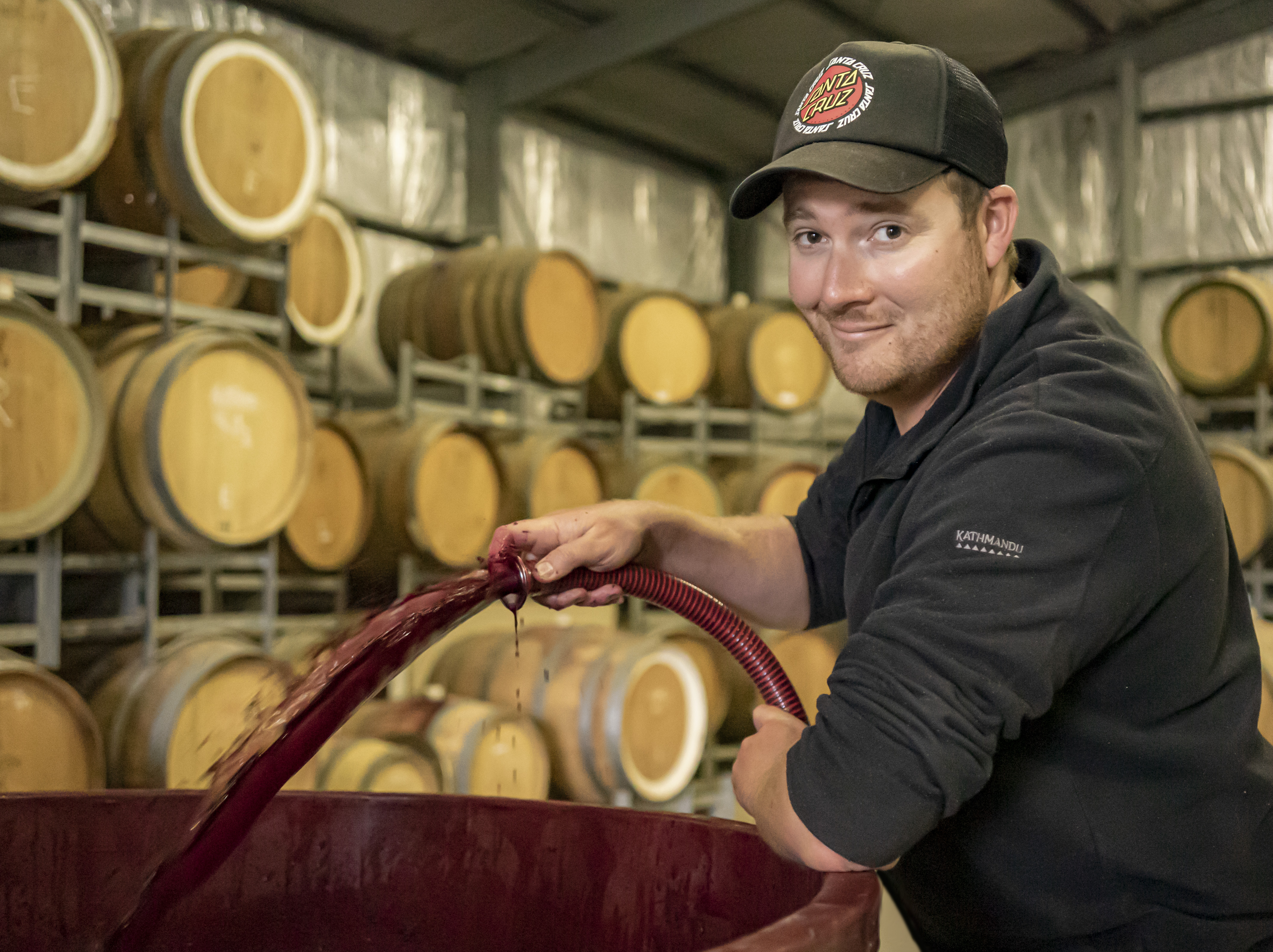 Man pumping wine into wine barrels 